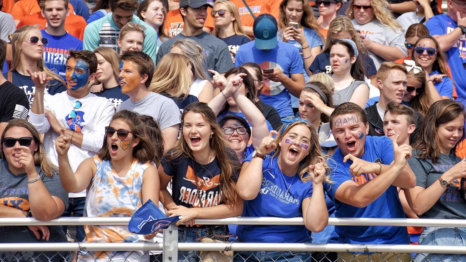 Hundreds of loud and energetic fans cheering in the student section at a home Marauders football game.